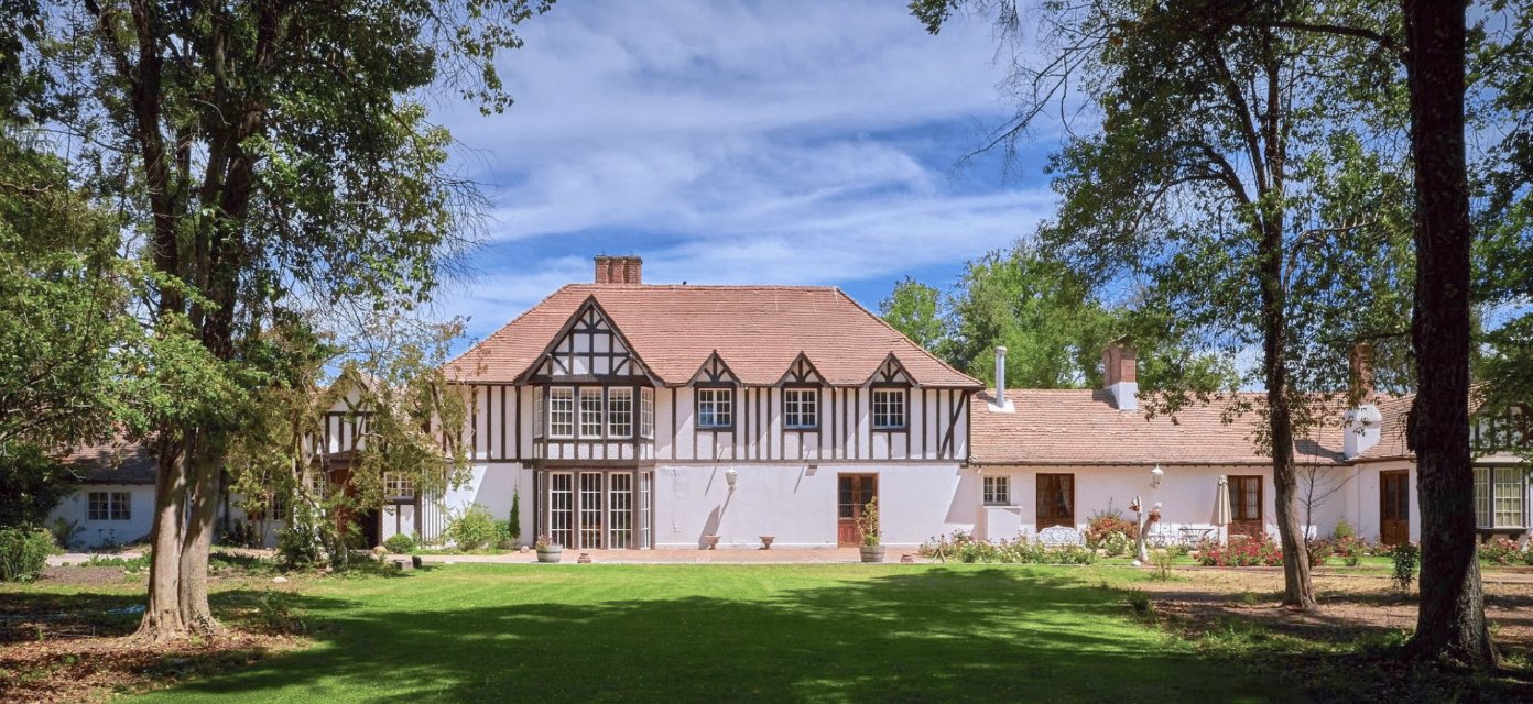 Tudor-style manor house and lawn under old trees outside Santiago